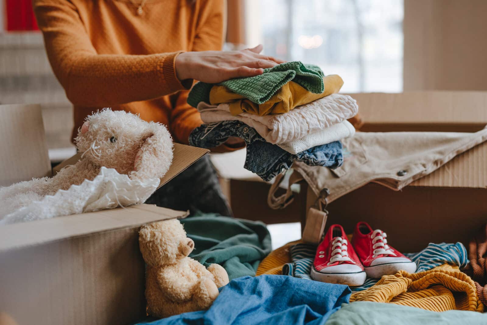 Nonprofit website design: a woman sorting toys and clothes into a box for charity