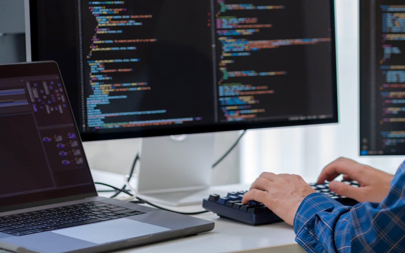 Custom web development: hands typing on a keyboard in front of monitors full of code