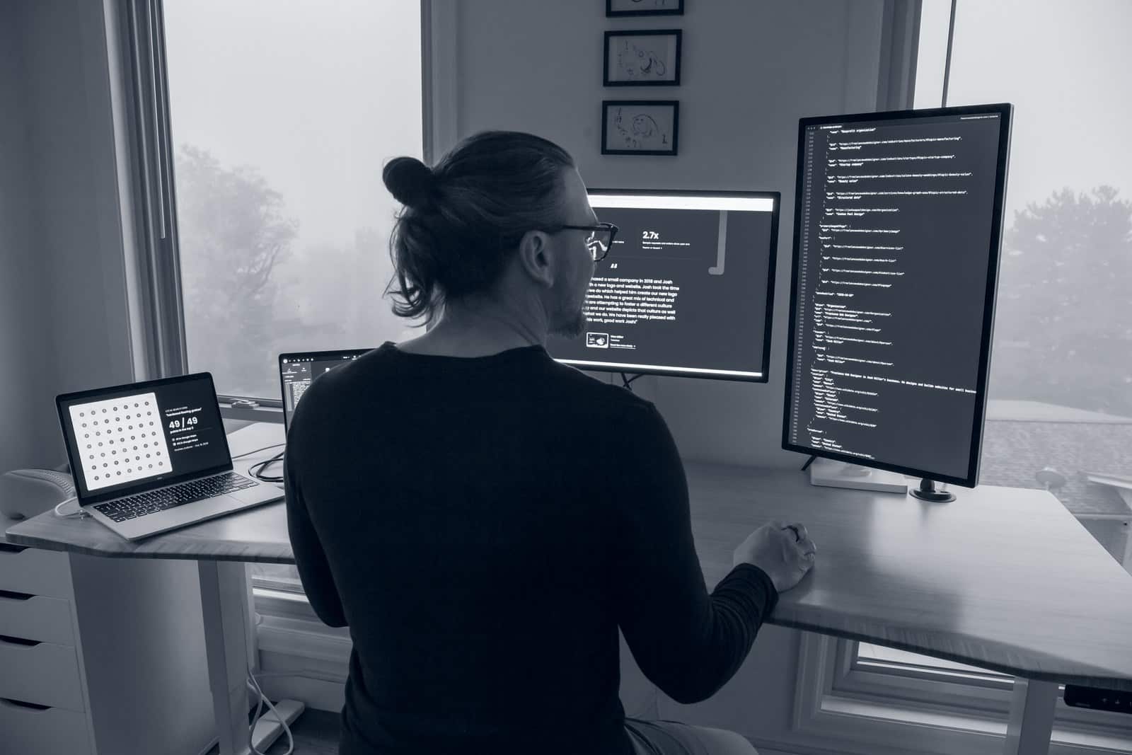 Josh Miller, WordPress developer, building a WordPress website at his desk, with code on a vertical monitor